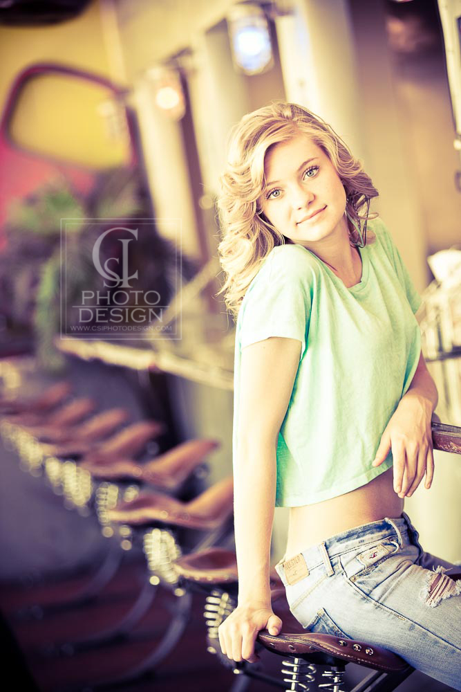 Senior girl in green top and jeans sitting on a cafe stool