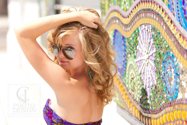 Senior girl with sunglasses and purple top against a bejeweled background