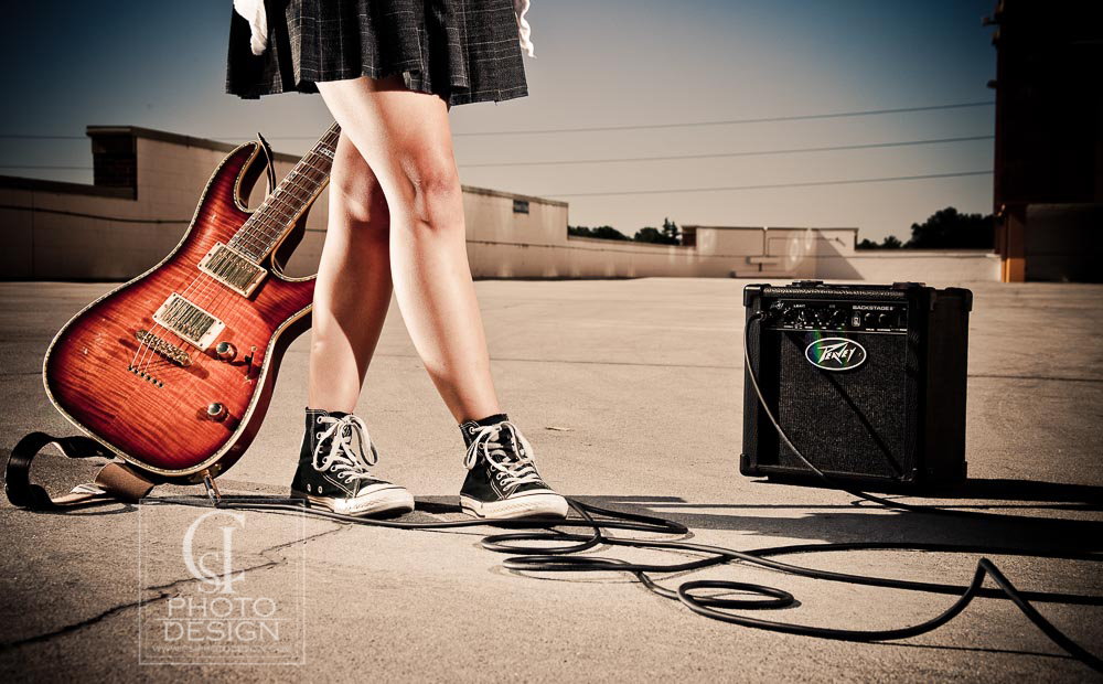 Senior girl with electric guitar and wearing Converse shoes on a parking garage